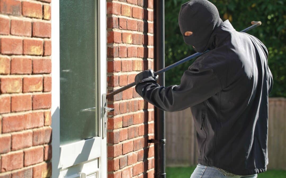 A burglar uses a crowbar to pry open the door of a homeowner who should have learned how to prevent burglary.